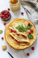 Healthy breakfast, celebrating Pancake day. Delicious homemade crepes with rasberries and peanut paste on a stone tabletop.