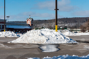 Snow plowed into large mounds in a parking lot in winter in Upstate NY.