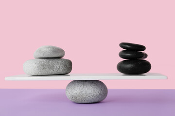 Spa stones on teeterboard against pink background. Concept of balance