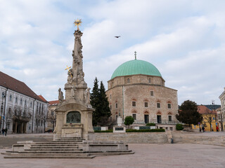 Fototapeta na wymiar Holy Trinity Statue and Mosque of Pasha Qasim on Szechenyi square in city of Pecs Hungary Europe