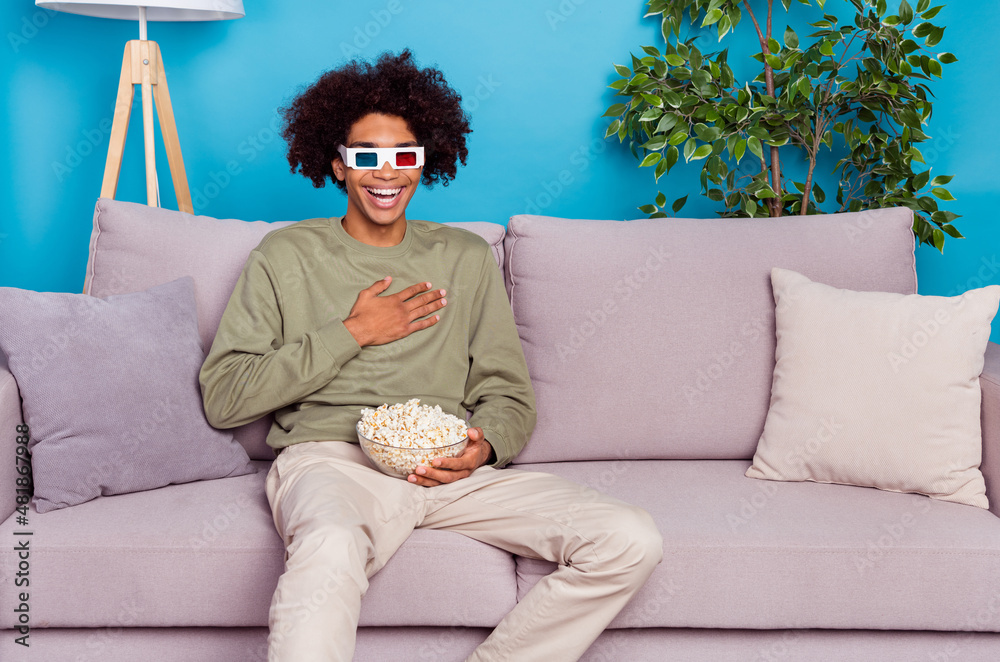 Poster Photo of young guy laughing hand on chest watch comedy humorous eat popcorn isolated over blue color background