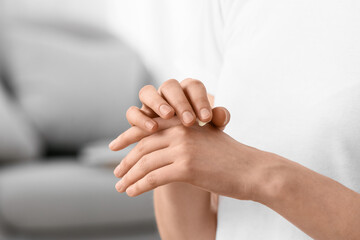 Young woman applying natural cosmetic cream onto her hands at home