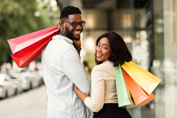 Portrait of happy black couple looking back with shopping bags