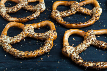 Fresh prepared homemade soft pretzels. Different types of baked bagels with seeds on a wood background.