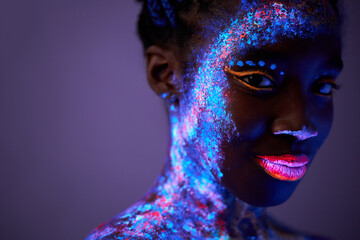 black lady with neon make-up body art posing looking at camera, isolated on purple. beautiful...