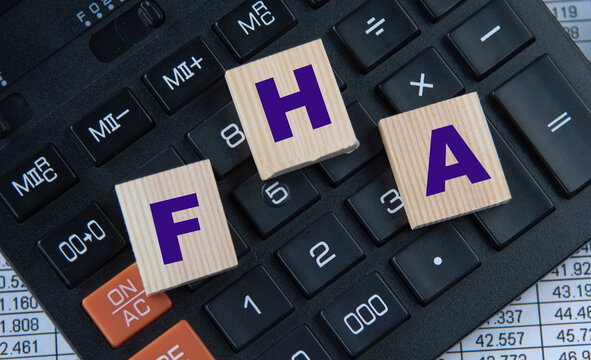 FHA - acronym on wooden cubes on the background of a calculator