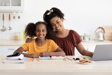 Loving black mother helping her daughter with homework