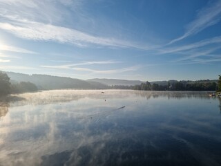 Obraz premium Early morning mist over the first basin of the Sorpesee (Sorpe lake), Sauerland, North Rhine-Westphalia, Germany, on a cold sunny day in October