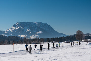 Blick auf Loipe  mit Wildem Kaiser im Hintergrund mit Schnee im Winter bei Blauem Himmel und Sonne