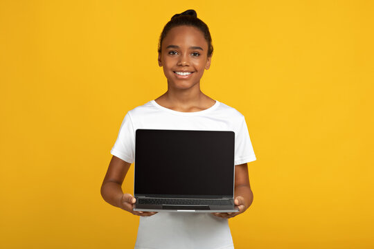 Smiling Pretty Teen African American Pupil Lady In White T-shirt Hold Laptop With Blank Screen