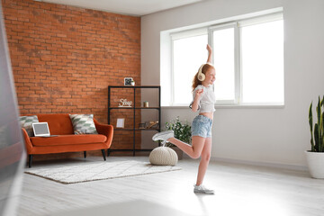 Little redhead girl in headphones dancing at home - Powered by Adobe