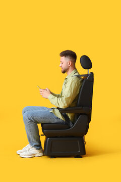 Young Man In Car Seat And With Phone On Color Background