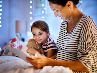 Engrossed in an interactive story. Cropped shot of an attractive young pregnant woman reading her daughter a bedtime story on a tablet.