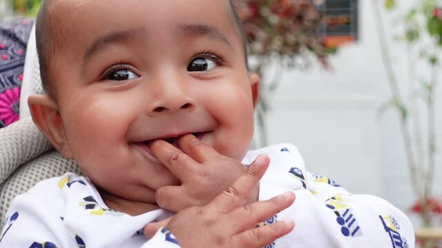 Cutest cheeks baby having fun on the mouth.  The cutest toddler's baby is having fun sitting on his mother's lap. Portrait of a cute baby boy. Close-up view.