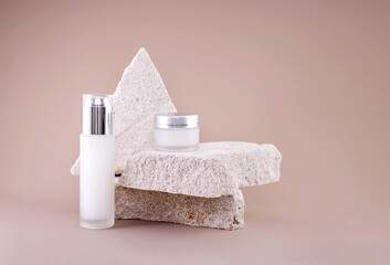 glass containers for natural cosmetics on a podium made of concrete stones on a brown background