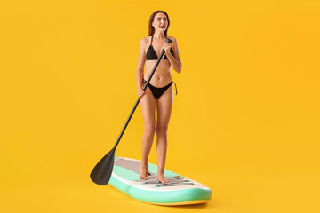 Young woman with board for sup surfing and oar on color background