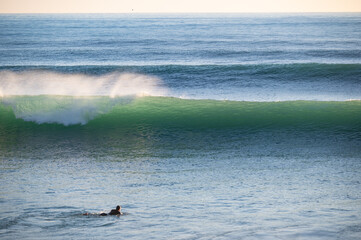 Fototapeta premium Surfer in front of big breaking Atlantic waves in Caños de Meca, Andalusia. Spanish surf spot with beautiful waves in winter