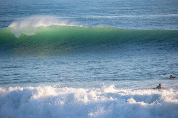 Surfer in front of big breaking Atlantic waves in Caños de Meca, Andalusia. Spanish surf spot with beautiful waves in winter
