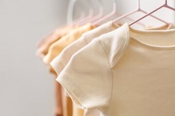 Rack with baby bodysuits in light children's room, closeup