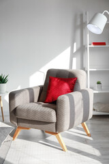 Soft armchair with red cushion in light living room