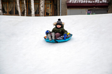 Fototapeta na wymiar boy riding downhill on a tubing sled