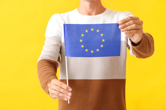 Young man with flag of European Union on color background