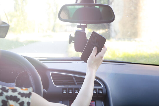 Woman inserting her cell phone in car phone holder	