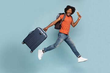 Excited black guy with backpack, luggage and passport going vacation