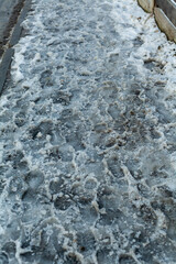 slippery sidewalk in winter covered with slush full of footprints