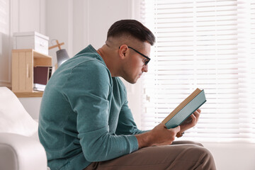 Man with poor posture reading book at home