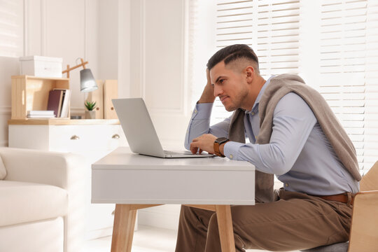 Man With Poor Posture Using Laptop At Table Indoors