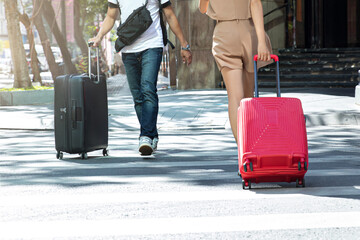male and female traveler walking with red and black suitcase in the city