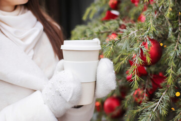 A thermostat in the hands of a girl in mittens on the street in winter
