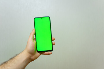 Man Using Smartphone with Chroma Key Screen . Shot with third-person view, blank green screen . Isolated man hands holding smartphone