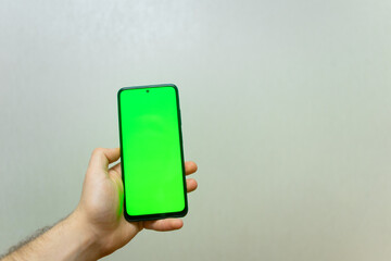 Man Using Smartphone with Chroma Key Screen . Shot with third-person view, blank green screen . Isolated man hands holding smartphone