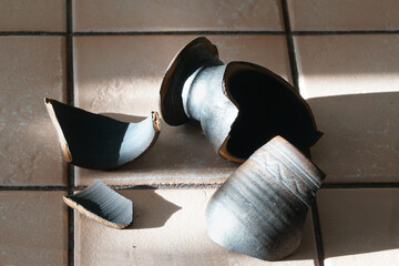 Broken ceramic wine glass on floor tiles