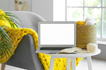 Laptop and knitting threads on table
