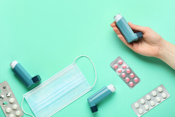 Female hand, asthma inhaler, medical mask and pills on color background