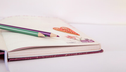 colored pencils on a notepad. notepad on a white background. red heart.