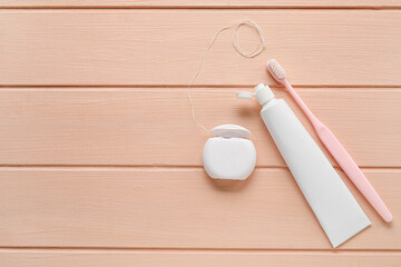 Dental floss with tooth brush and paste on pink wooden background