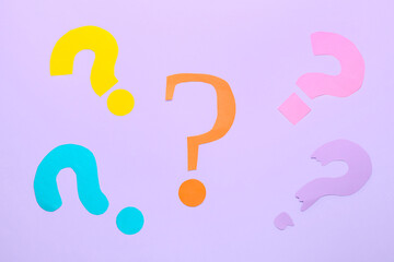 Question marks made of paper on lilac background