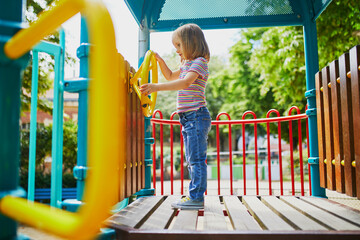 Girl on playground on a sunny day. Preschooler child playing on a slide. Outdoor activities for kids