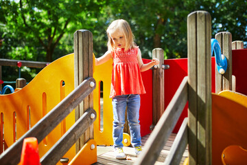 Girl on playground on a sunny day. Preschooler child playing on a slide. Outdoor activities for kids