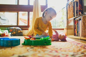 Adorable toddler girl playing with toys on the floor at home. Indoors activities for kids