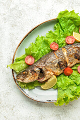 Plate with delicious sea bass fish and vegetables on light background, closeup