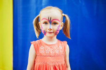 Little preschooler girl with butterfly face painting outdoors