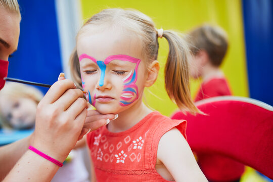 Artist painting little preschooler girl like butterfly. Creative activities for kids