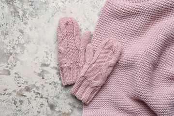 Knitted mittens and scarf on grunge background, closeup