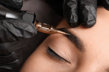 Young woman undergoing procedure of permanent eyebrow makeup in tattoo salon, closeup - obrazy, fototapety, plakaty