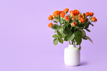 Vase with beautiful orange roses on purple background